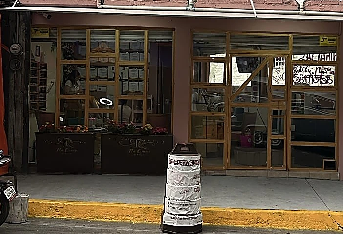 Fachada del salón: ventanales con marco dorado y jardineras con flores sobre la banqueta de San Federico