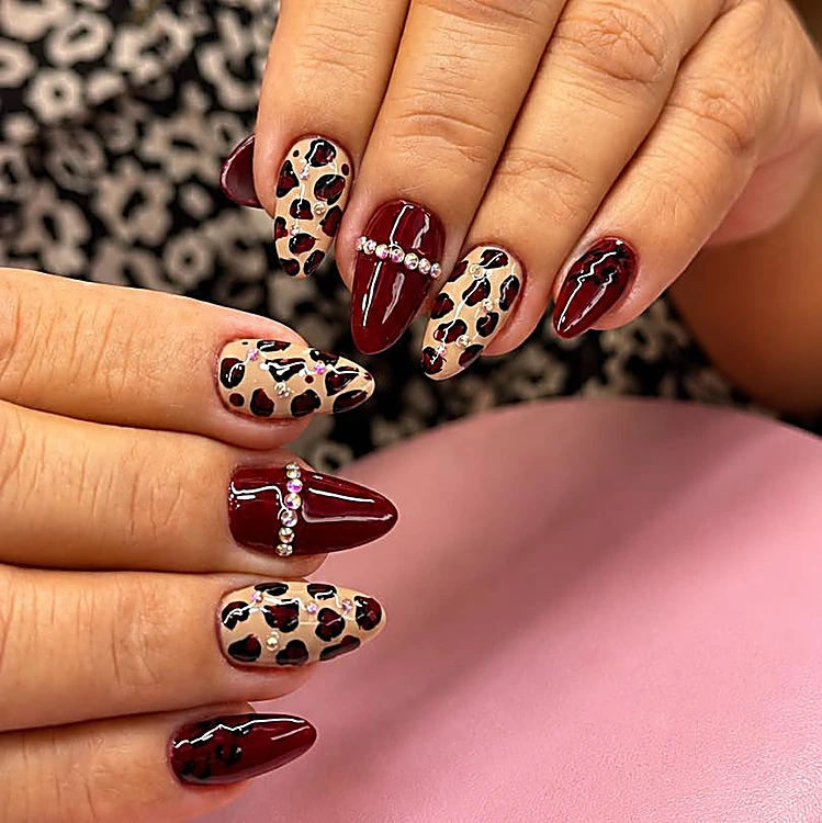 Uñas en borgoña y animal print con una línea de piedras