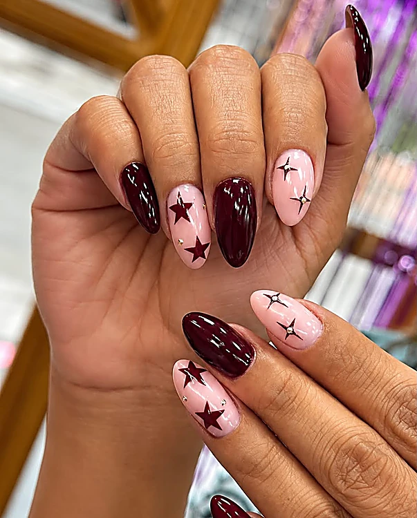 Uñas almendra en burdeos y rosa con estrellas