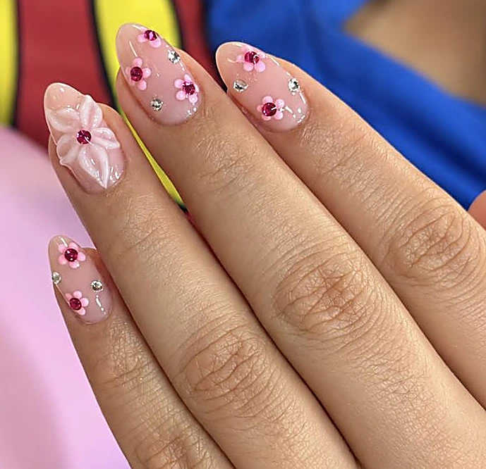 Uñas almendra nude con flores rosas en relieve y cristales