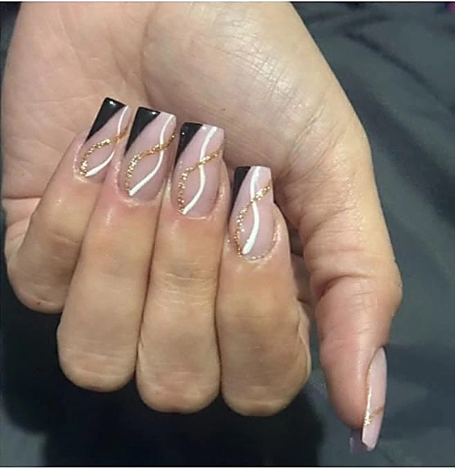 Uñas largas en nude con puntas negras y línea dorada